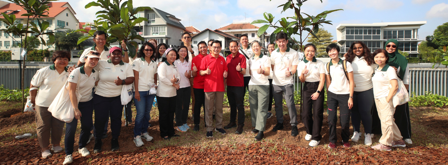 Group of people in polos with thumbs up, outdoor setting, modern houses in the background.